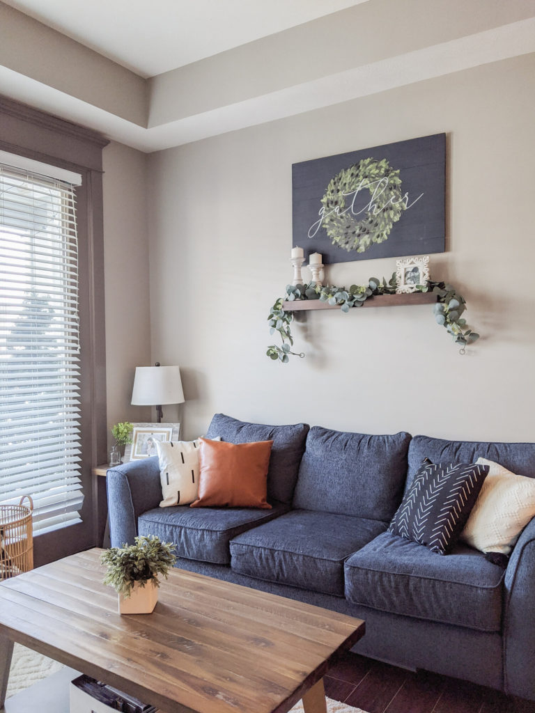 a navy blue couch decorated with modern boho pillows in a small apartment living room